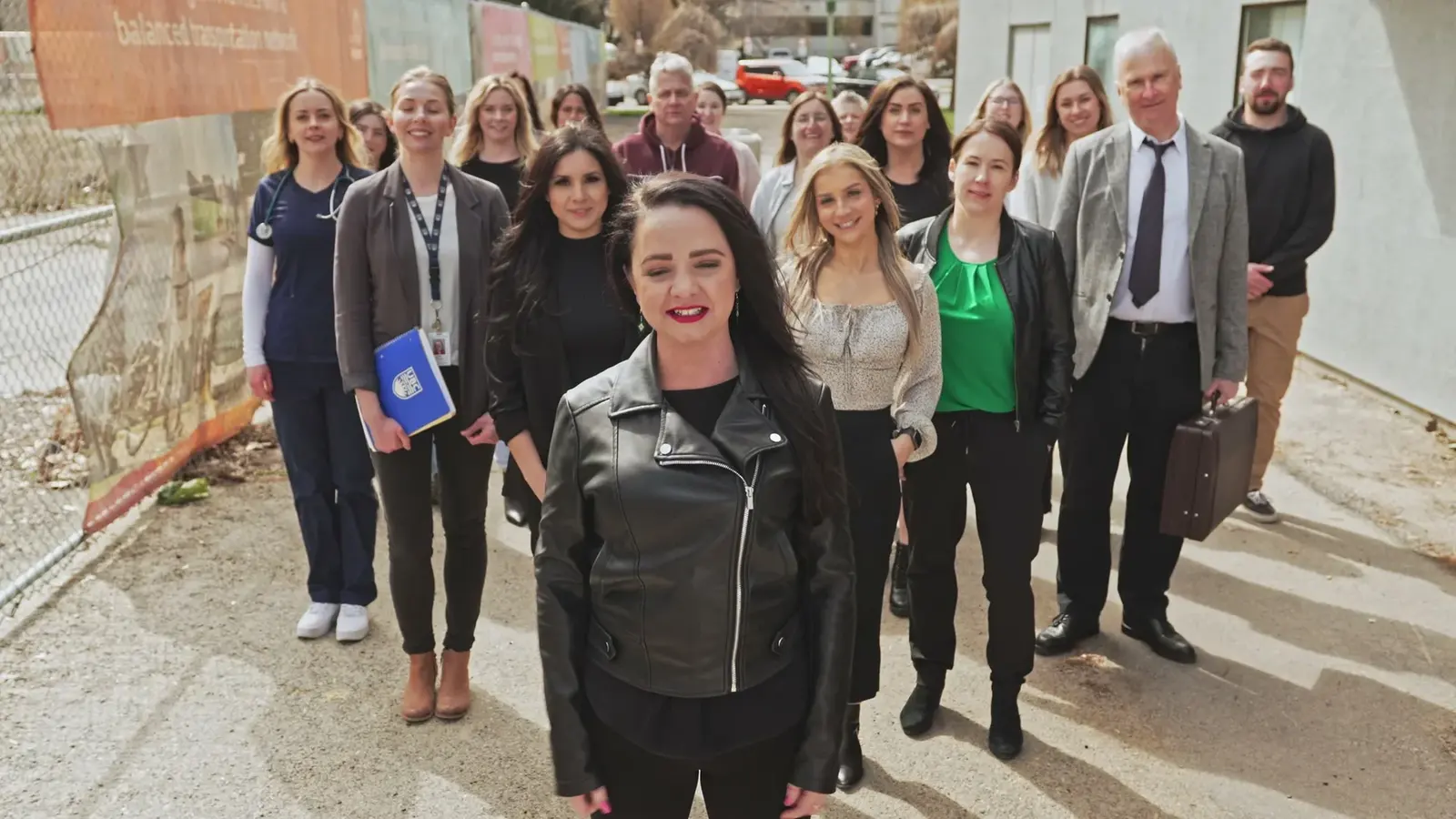 A group gathers behind a woman walking toward the camera.