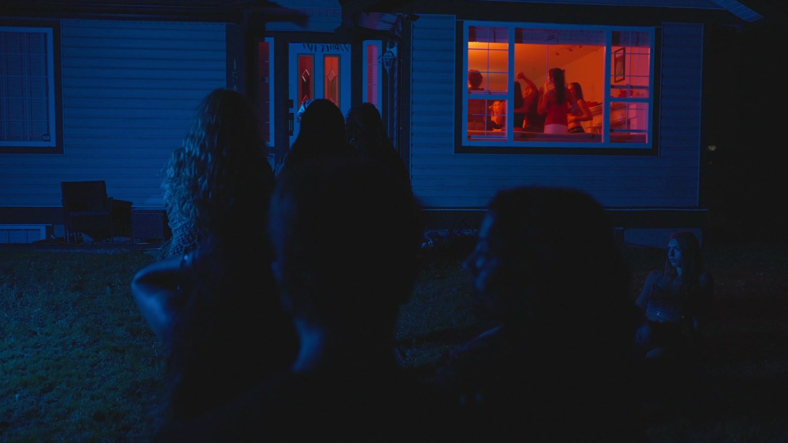 The house party seen through contrasting blue exteriors and warm window light.
