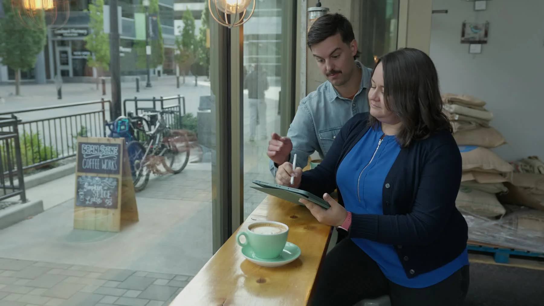 Liz and Dylan Ranney review a mural sketch on a tablet beside a coffee cup.